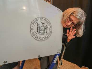 Person peeking over voting booth during early voting in NYC